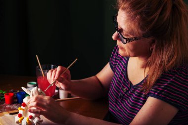 Sanatçı bardaklarda tasarım çalışmaları gerçekleştirir. Bahar, sıcak ruh hali. Masaya willow ve Lila yeşil çiçek yaprakları ile dalları vardır. Çok renkli Paskalya tavşanı.