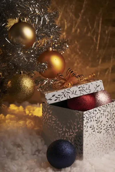 Σε ένα χρυσό φόντο, ένα χριστουγεννιάτικο δέντρο με παιχνίδια και ένα δώρο bo — Φωτογραφία Αρχείου