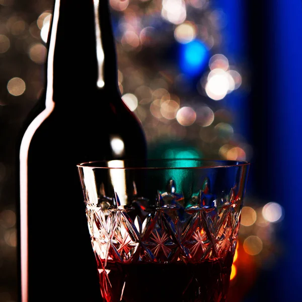 Wine bottle with a crystal glass standing on a table. Blue backg