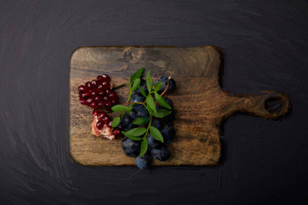 top view of painted cutting board with grapes and pomegranate seeds on black 