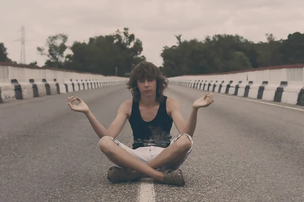 Jovem está meditando na estrada principal, o desenvolvimento da alma e da natureza — Fotografia de Stock