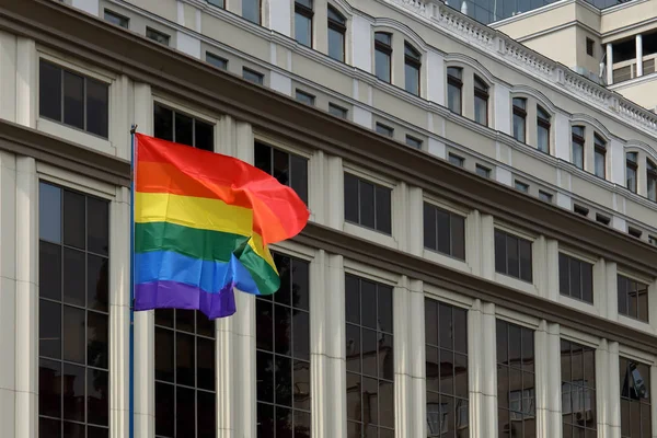 La bandera del orgullo LGBT del arco iris sopla contra la construcción de fachada sobre el desfile del orgullo —  Fotos de Stock