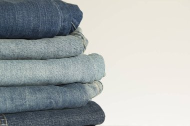 Yeni kot pantolon giyim kazık arka plan. Dükkan beyaz arka plan üzerinde mavi kot yığını