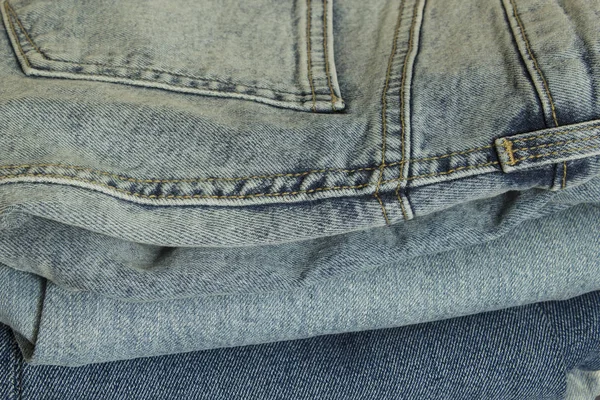 Blauwe nieuwe jeans broek kleren stapel achtergrond — Stockfoto