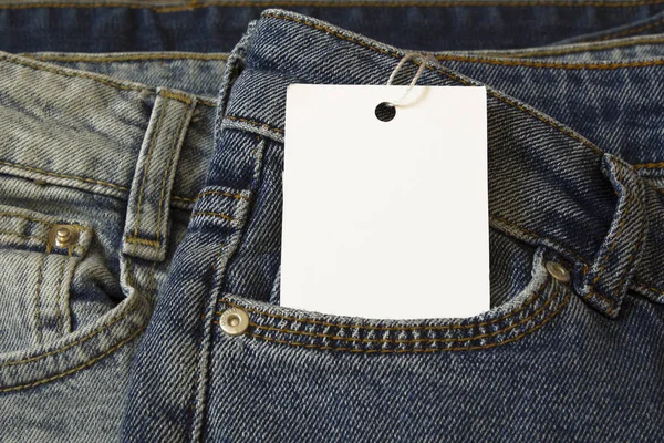Label price tag mockup on blue jeans from white paper.