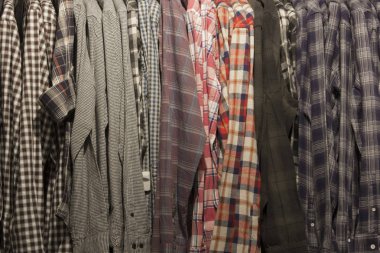 Çeşitli ekose doku ile erkek gömlek asılı Raf
