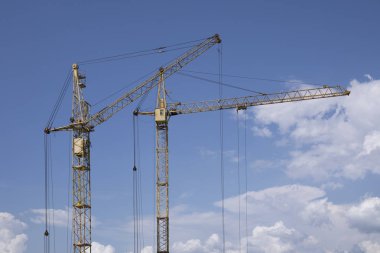 Mavi bulutlu gökyüzüne karşı iki inşaat vinçleri arasındaki boşluk kopyalamak