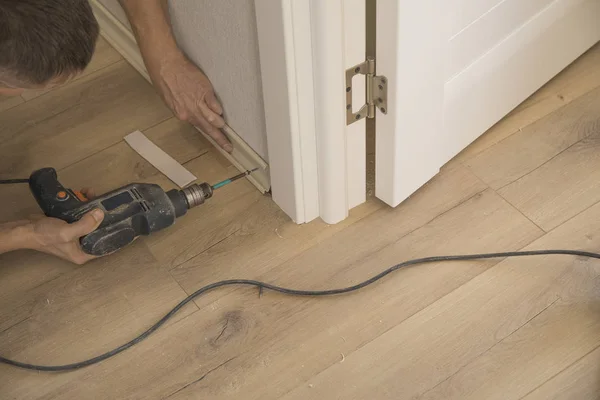 Repairmans hands Installing Skirting Board Handyman repairing with hammering a nile