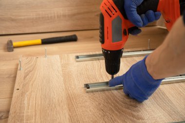 Profesyonel marangoz ustası içeride tornavidayla çalışıyor.