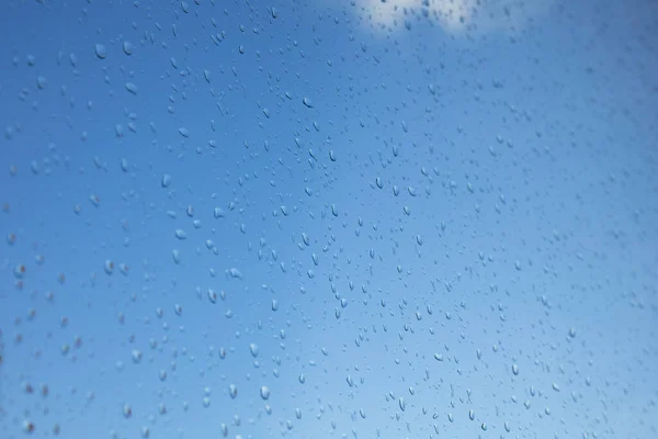透过玻璃上有雨滴的窗户 可以看到晴朗的蓝天 雨后天气图 — 图库照片