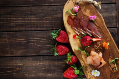 Düz bir arka plan, ahşap tahta, çilek ve mikro yeşillik üzerinde soğuk kesim. Metin için ücretsiz yer