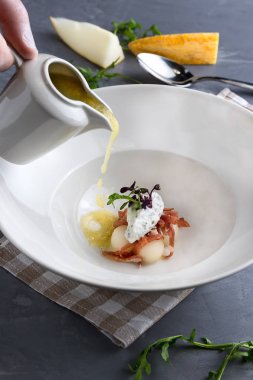 Nane, proshuto ve salatalık ile tureen kavun çorbası dökülen. Beyaz tabak, gri arka planda kaşık. Close