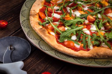 Buffalo mozzarella, domates ve taze fesleğen ile Closeup Pizza Margherita. Pizza kesici ahşap arka plan üzerinde yatıyor. Geleneksel İtalyan fast food