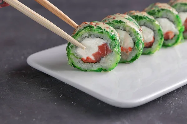 Comer Sushi com chopsticks.Closeup Sushi rolo comida japonesa no restaurante — Fotografia de Stock