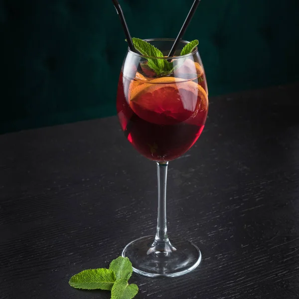 Sangria fredda in un bicchiere di vino con menta. Tavolo in legno nero in un ristorante — Foto Stock