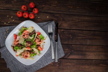 Prosciutto ve parmesan ile salata. Masada Kiraz Domates, çatal bıçak, bıçak, çatal ve çam fıstığı. Düz yatıyordu yatay fotoğraf. Metin için boş alan