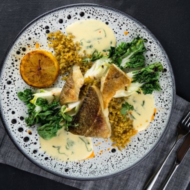 Baharatlı bulgur ve kızarmış Pak-choi ve limon ile benekli kurt balığı fileto. Üstte görüntü