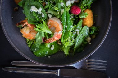 Brie peynir, ahududu, ceviz ile Tiger karides salatası yakından görünümü. Gri arka plan üzerine ahşap tahta