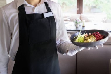 Garson bir restoranda kurutulmuş kızılcık ve daikon ile sığır tarran bir tabak tutan