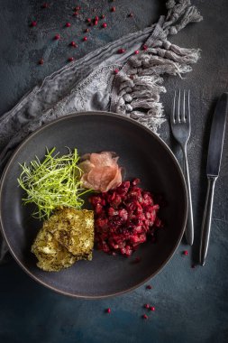 Kurutulmuş kızılcık ve gri arka plan üzerinde daikon ile Sığır tar-katran. Kaşık, çatal ve gri masa örtüsü