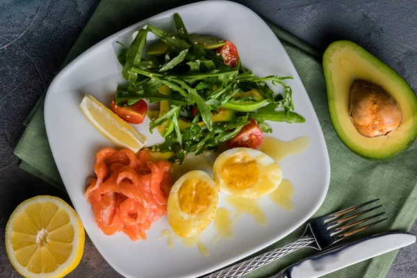 Salade à la truite salée, avocat, roquette et oeuf frit au beurre. Couverts sur le fond gris — Photo