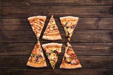 Koyu kahverengi retro panoları üzerinde jambon, zeytin, mantar ve peynir ile dilimler halinde lezzetli taze pizza kesin. Üst görünüm . Ahşap masaüzerinde Pizza.