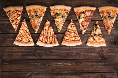 Koyu kahverengi retro panoları üzerinde jambon, zeytin, mantar ve peynir ile dilimler halinde lezzetli taze pizza kesin. Üst görünüm . Ahşap masaüzerinde Pizza.