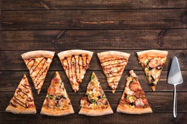 Jambon, zeytin, mantar, peynir ve koyu kahverengi retro panoları üzerinde bir pasta spatula ile dilimler halinde lezzetli taze pizza kesin. Üst görünüm . Ahşap masaüzerinde Pizza.