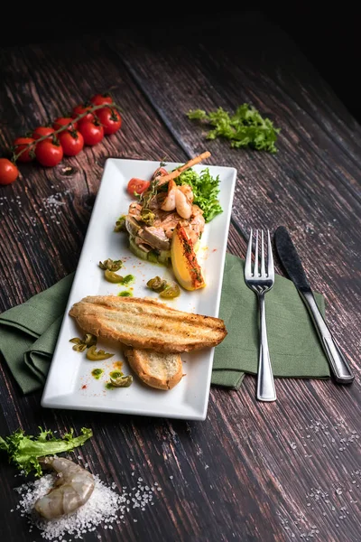 Cevada de salmão com camarão, laranja, tomate cereja, alface, pepinos e croutons em fundo escuro de madeira perto. Conceito de comida saudável em estilo rústico — Fotografia de Stock