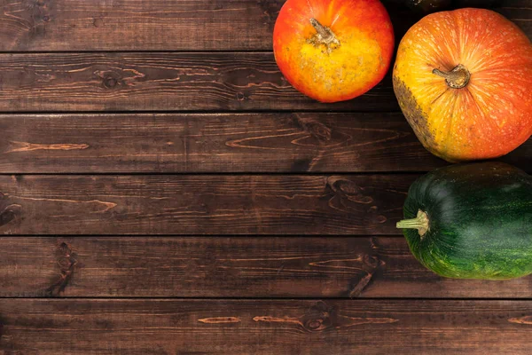 Осенняя творческая концепция с зелеными, желтыми, красными и оранжевыми тыквами на коричневом деревянном фоне. Плоская кладка, вид сверху, копировальное пространство — стоковое фото
