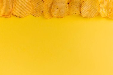 Üst görünüm sarı zemin üzerinde altın çipler, yiv deseni ve fotokopi alanı için fast food dokusu