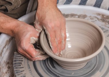 Potter, stüdyoda çömlekçinin çember üzerinde geniş bir kase beyaz kil yapıyor. Yaratıcılık ve sanat kavramı, yatay fotoğraf.