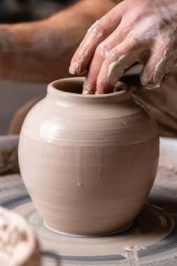 Potter stüdyodaki tekerlek çemberinde bir kavanoz ya da bir tencere beyaz kil yapıyor. Yaratıcılık, sanat ve el işi kavramı