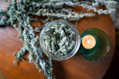 Sağlıklı çay içebilmek için kavanozdaki mugwort 'u evdeki yuvarlak ahşap masaya koydum. Boho yaşamı ve alternatif sağlık