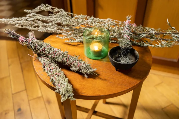 Teknenin içindeki ahşap masadaki kötü enerjiyi temizlemek için ev yapımı temizleme çubuklarına dönüştürülmüş mugwort hasadı. Boho yaşamı ve alternatif sağlık
