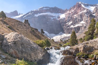 Temiz mavi gökyüzü, kayalık tepeler ve Tacikistan 'daki Fann dağlarındaki taze dağ deresi ile güzel dağ yürüyüşü yolu.