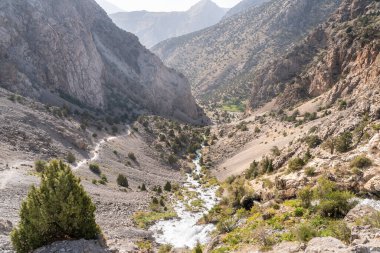 Temiz mavi gökyüzü, kayalık tepeler ve Tacikistan 'daki Fann dağlarındaki taze dağ deresi ile güzel dağ yürüyüşü yolu.