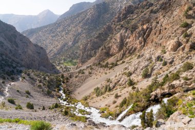 Temiz mavi gökyüzü, kayalık tepeler ve Tacikistan 'daki Fann dağlarındaki taze dağ deresi ile güzel dağ yürüyüşü yolu.