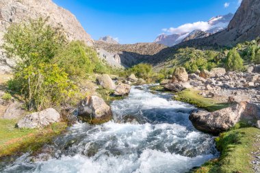 The beautiful mountain trekking road with clear blue sky and rocky hills and fresh mountain stream in Fann mountains in Tajikistan clipart