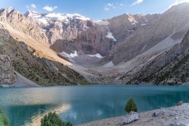 Pamir sıradağları manzarası ve Tacikistan 'daki Fann Dağları' ndaki Kulikalon Gölü 'ndeki huzurlu kamp alanı. Saf buz gölünün rengarenk yansıması.