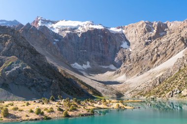 Pamir sıradağları manzarası ve Tacikistan 'daki Fann Dağları' ndaki Kulikalon Gölü 'ndeki huzurlu kamp alanı. Saf buz gölünün rengarenk yansıması.