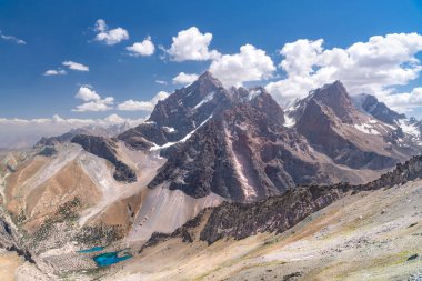 The beautiful mountain trekking road with clear blue sky and rocky hills and the view of Alaudin lake in Fann mountains in Tajikistan clipart