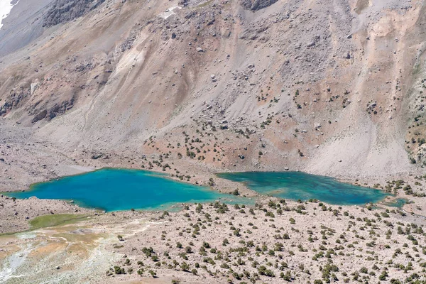 The beautiful mountain trekking road with clear blue sky and rocky hills and fresh mountain lake in Fann mountains in Tajikistan