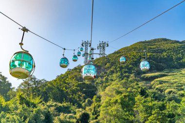 Teleferiğin güneşli manzarası ve okyanus kenarındaki eğlence parkı.