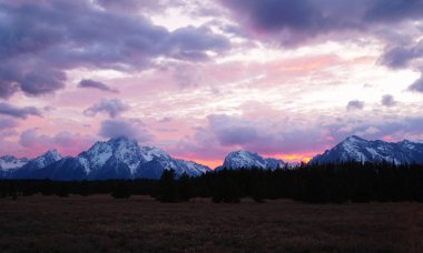 Grand Tetons Milli Parkı'nın görkemli zirveleri üzerinde ateşli bir gün batımı