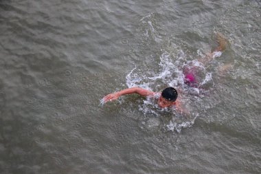 Bir çocuk nehirde eğlenceli bir şekilde yüzüyor..