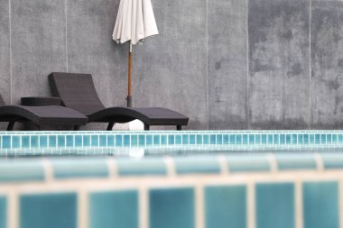 Sandalye ve şemsiye, yüzme havuzunun yanında.