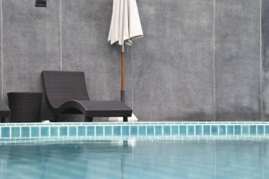 Sandalye ve şemsiye, yüzme havuzunun yanında.