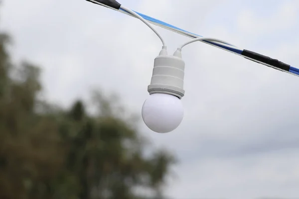 Round light bulb with a sky backdrop. White light bulb with blurred background.