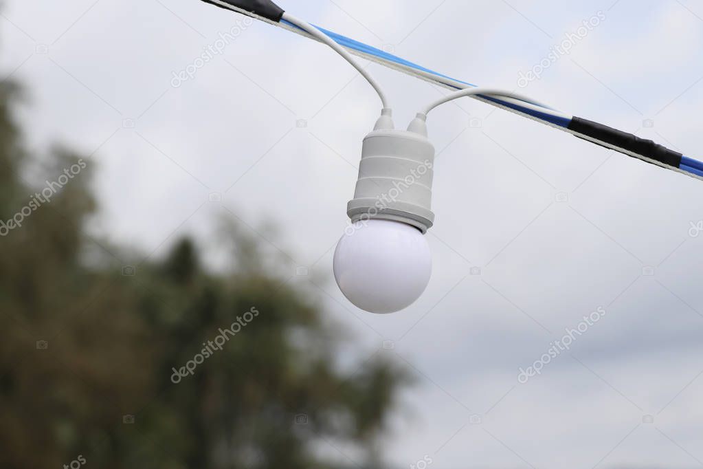 Round light bulb with a sky backdrop. White light bulb with blurred background.